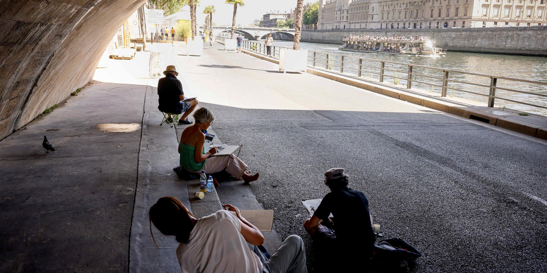 En grupp människor söker skugga under en bro vid floden Seine i Paris. Arkivbild