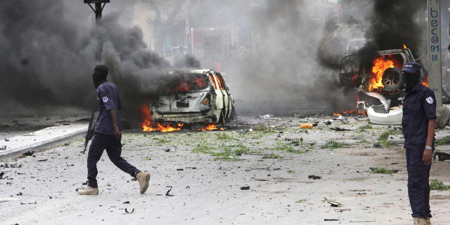 Somaliska soldater passerar framför brinnande bilar efter en attack vid ett köpcenter i Mogadishu i juli i år. Arkivbild.