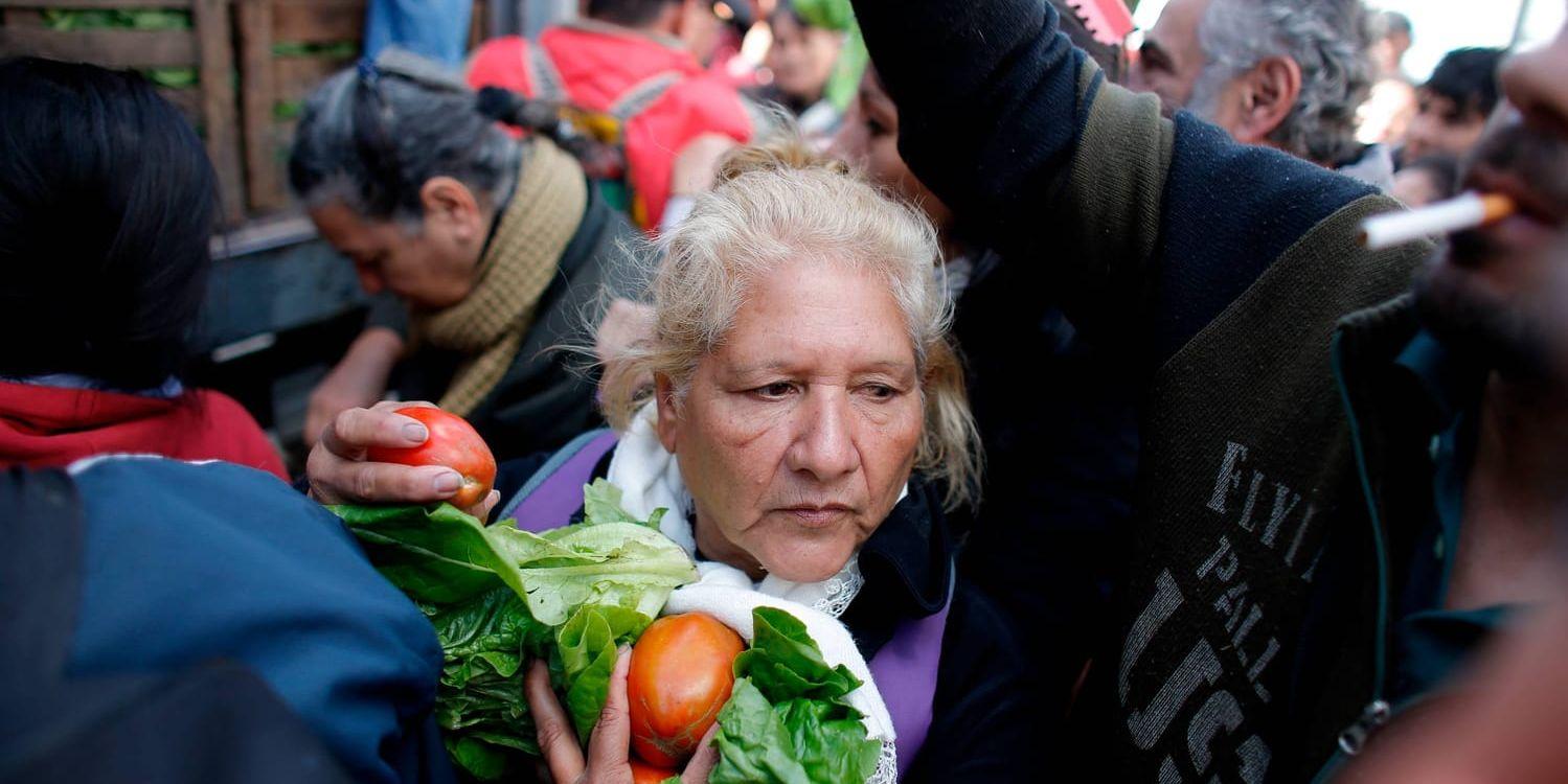 En kvinna tar sig genom folkmassan efter att ha fått gratis grönsaker på torget i Buenos Aires, Argentina.