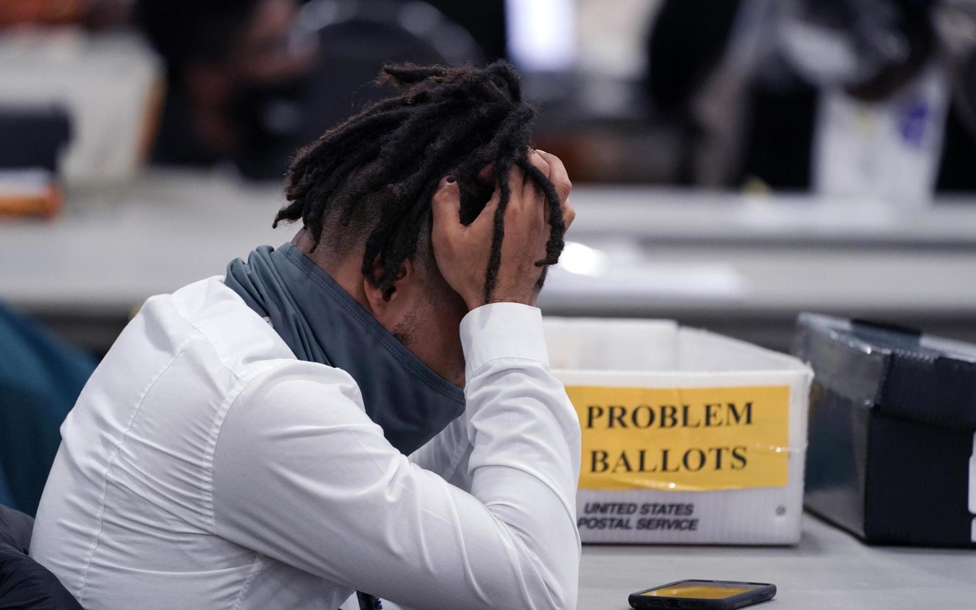 En valarbetare i Detroit, Michigan, tar sig för huvudet under slutarbetet med rösträkningen.