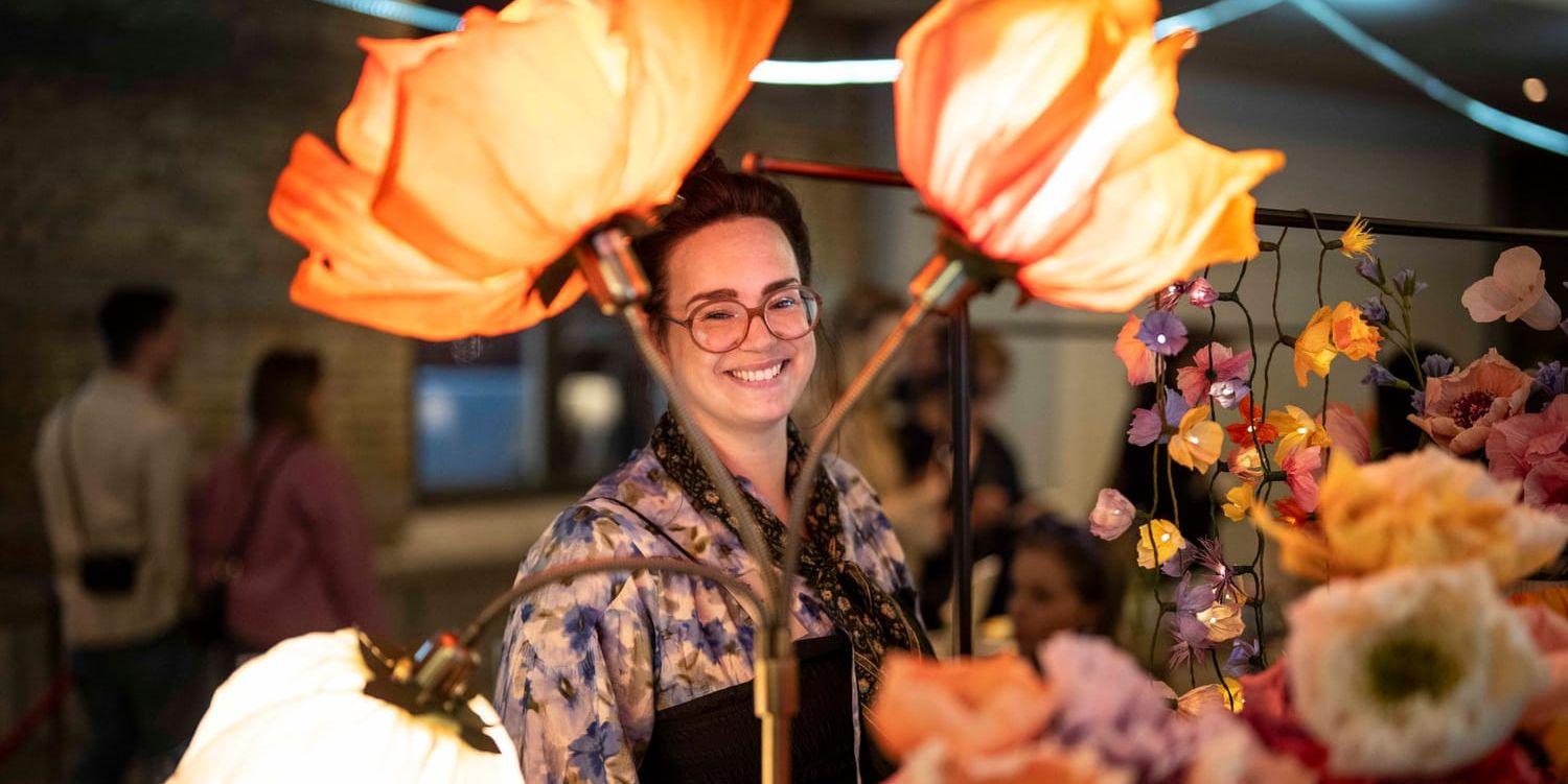 Utställaren Josefine Johansson tittar fram mellan blommorna i italienskt crepepapper.