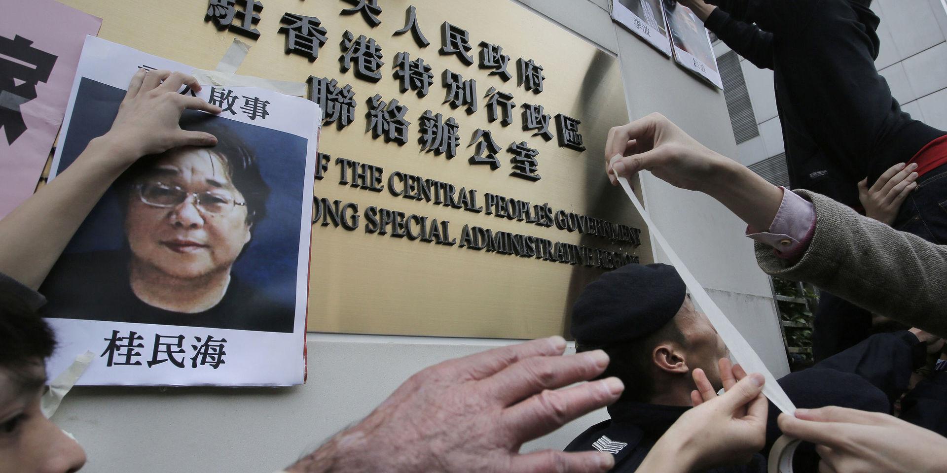 Protestanter sätter upp bilder på saknade bokförsäljare, på bild Gui Minhai, utanför Kinas de facto-ambassad i Hong Kong. 