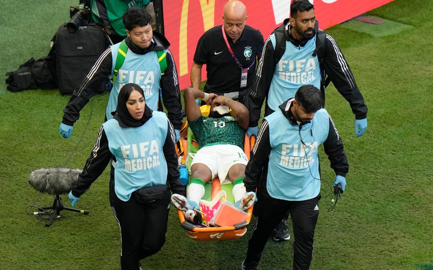Yasser Al-Shahrani bärs ut på bår efter att ha fått ett knä i ansiktet. 