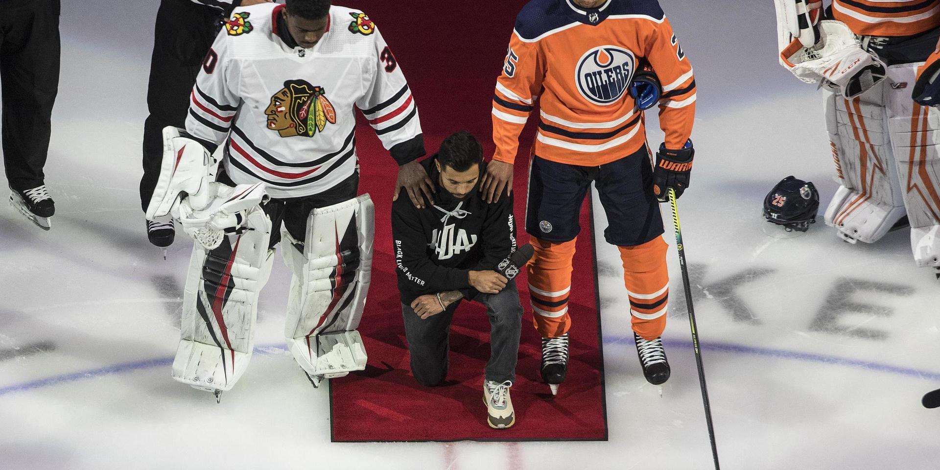 Minnesotas Matt Dumba knäböjer under USA:s nationalsång, flankerad av Chicagos Malcolm Subban och Edmontons Darnell Nurse, när NHL inledde playoffserien med att markera mot rasism. 