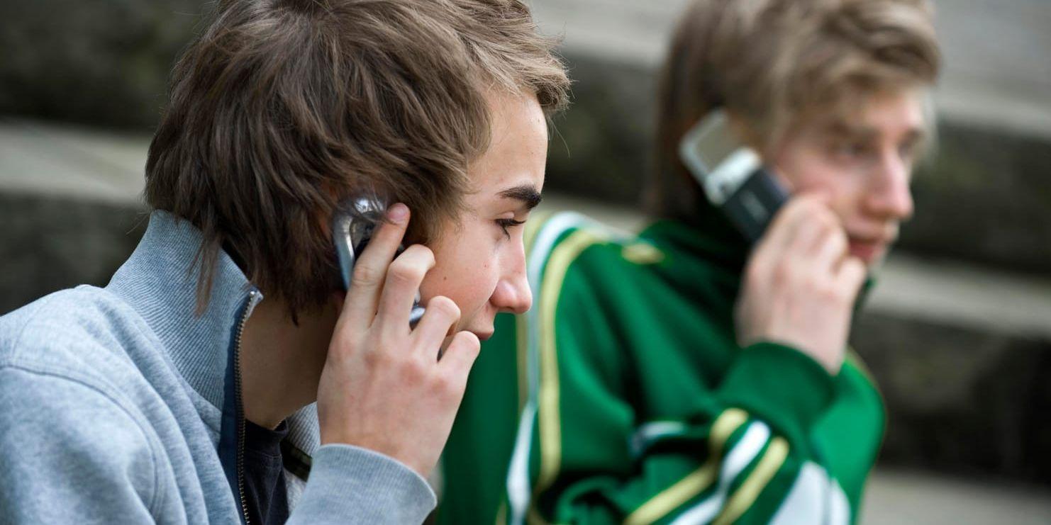 Två tonårskillar använder sina mobiltelefoner. Arkivfoto.