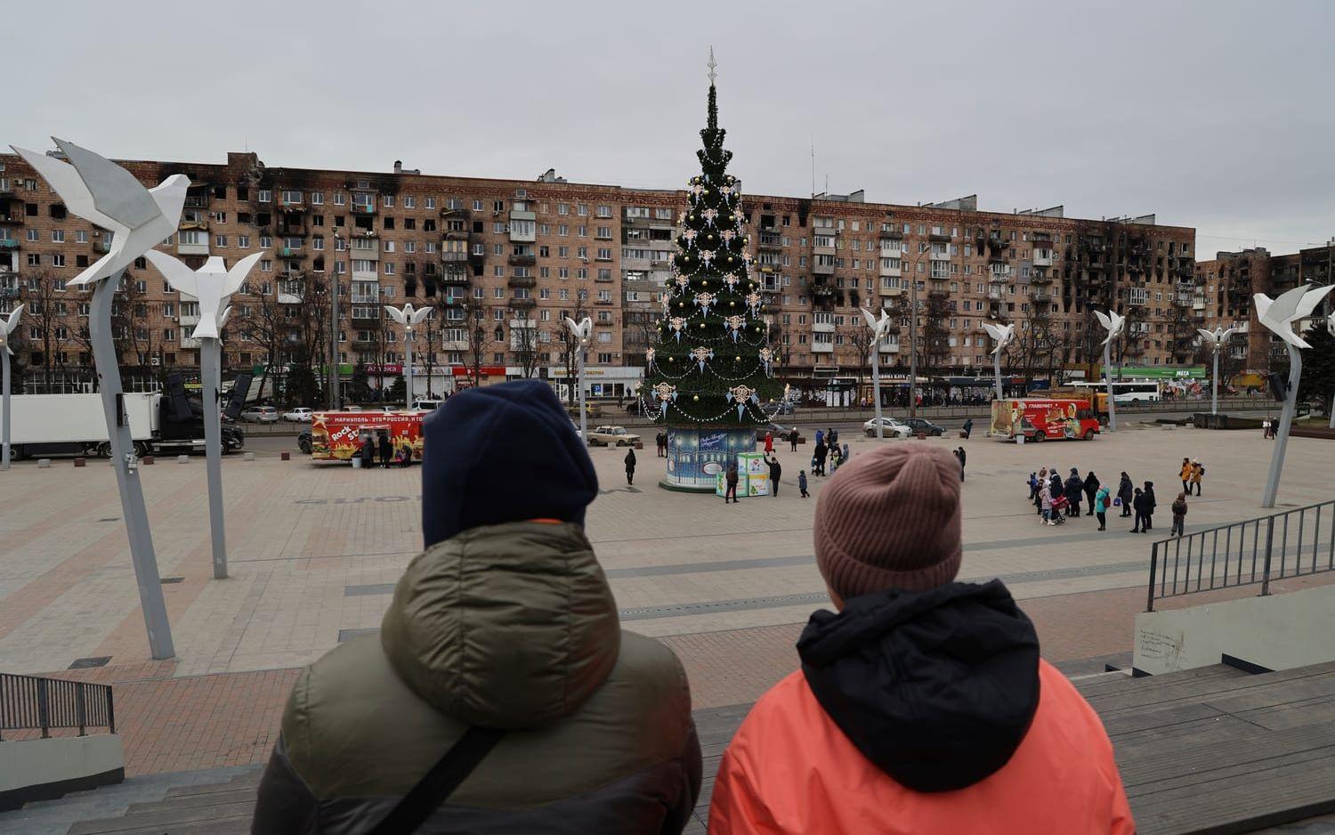 Mariupolbor vid ett torg med en julgran som pyntats för den ryskortodoxa julen på torsdagen.