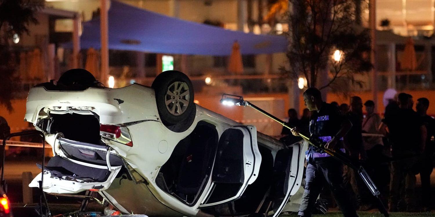Israelisk polis och räddningstjänst arbetar vid bilen som var involverad i attacken på en strandpromenad i Tel Aviv i fredags.