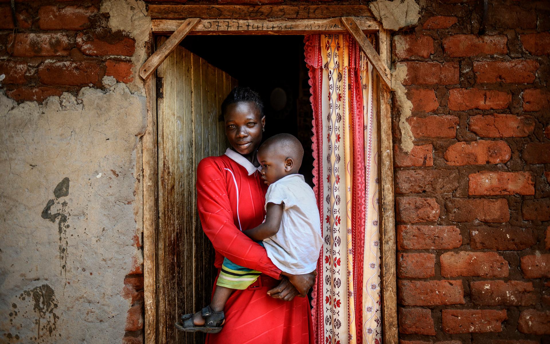 Sarah Mdondo, här med sonen Paul, framför sitt hus i byn Tongolo. Hon har fem barn, och har på nära håll märkt vad tillgången till rent vatten fört med sig. ”Tidigare var barnen sjuka ofta, vi fick köpa dyra mediciner. Nu är de sällan sjuka utan kan gå i skolan”, säger hon. 