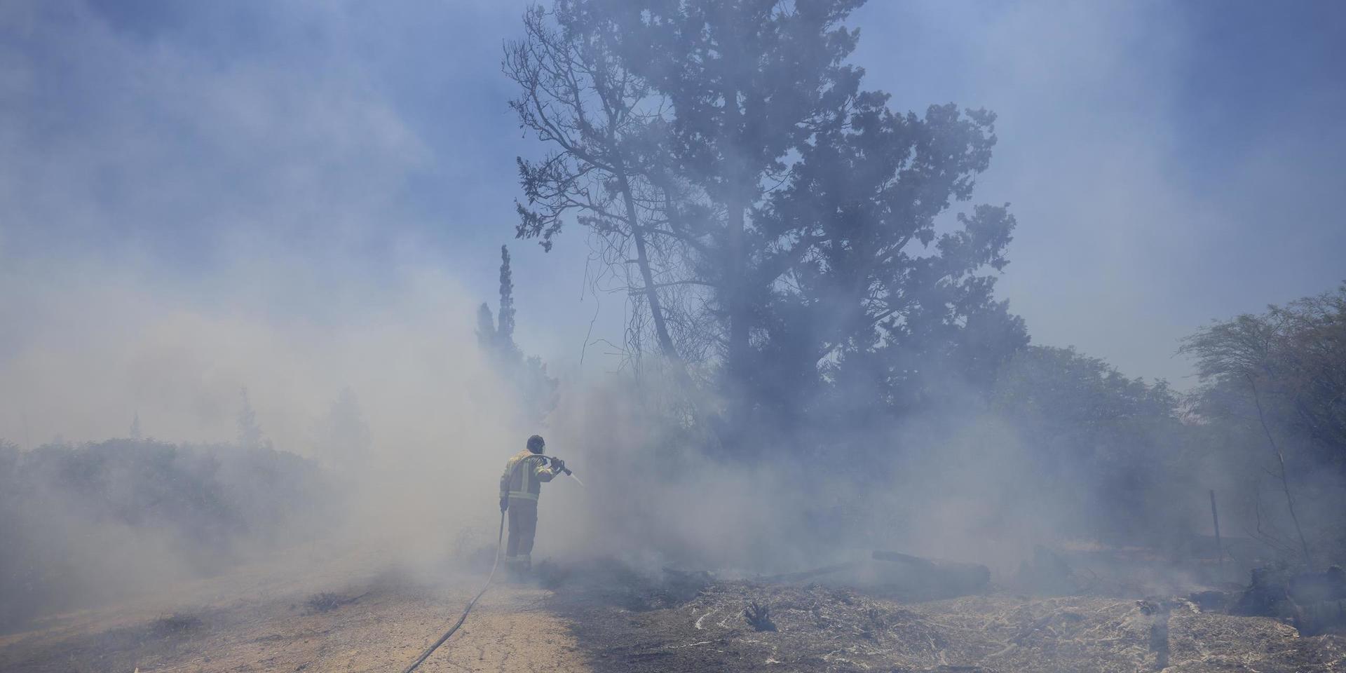 En israelisk brandman försöker släcka en brand som orsakats av ballonger från Gazaremsan under tisdagen.