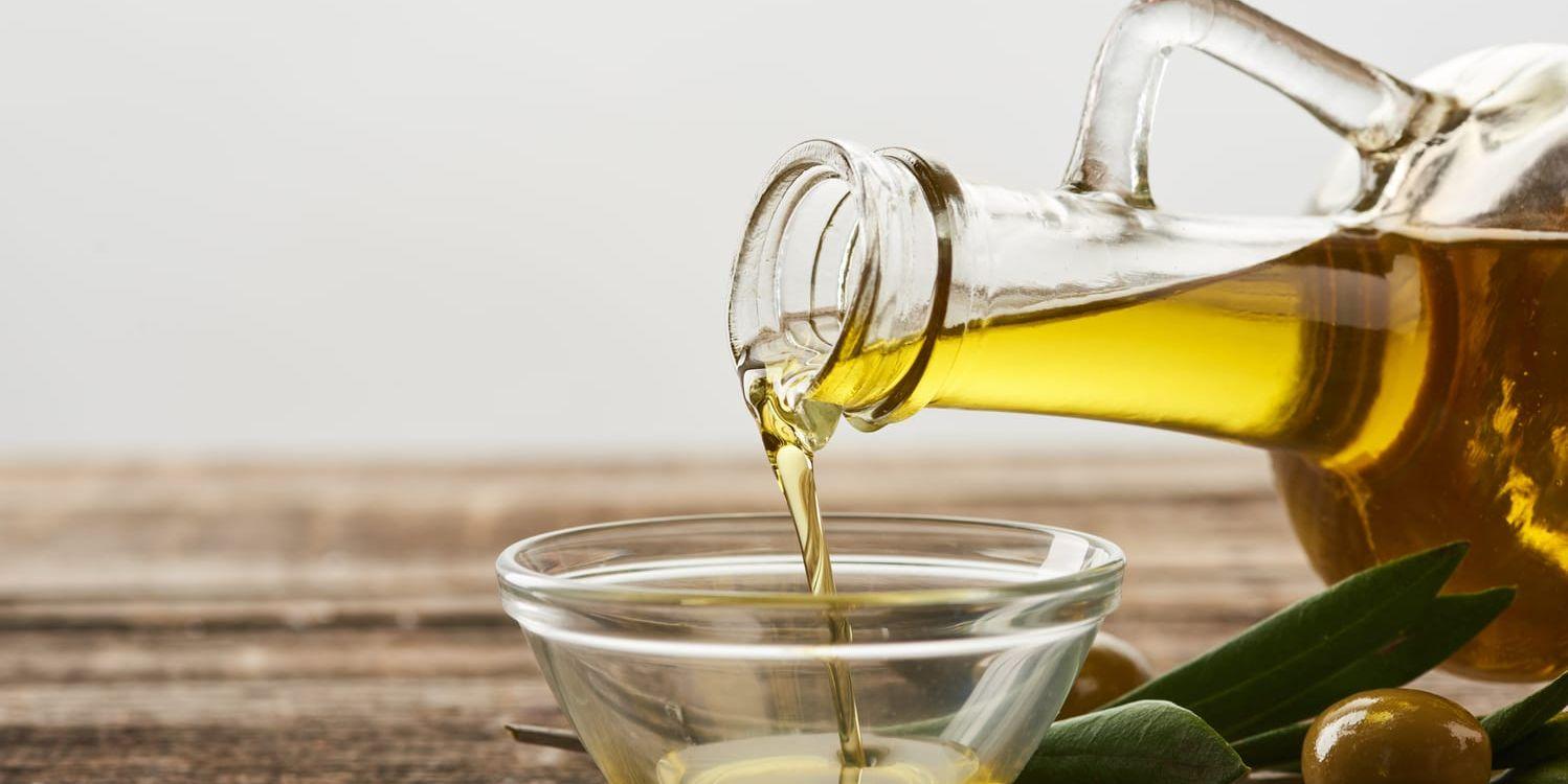 Närbild på en flaska med olivolja som hälls upp i en glasskål.