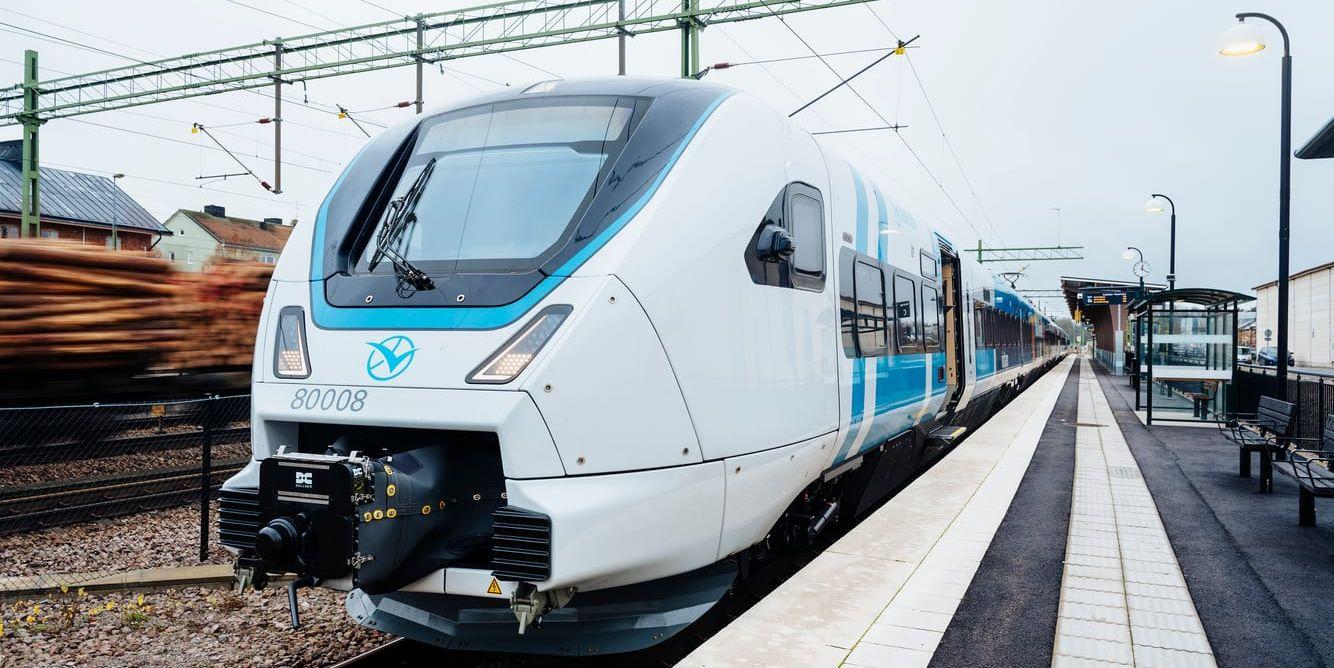 Ett vitt och blått tåg av modellen X80 står parkerad vid en perrong.