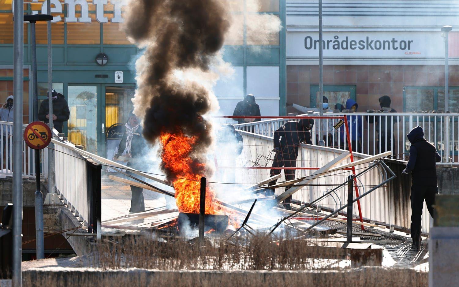 Personer gör en barikad med brinnnade bildäck och andra föremål vid Ringdansen centrum, i samband med upplopp i Navestad i Norrköping på påskdagen.
