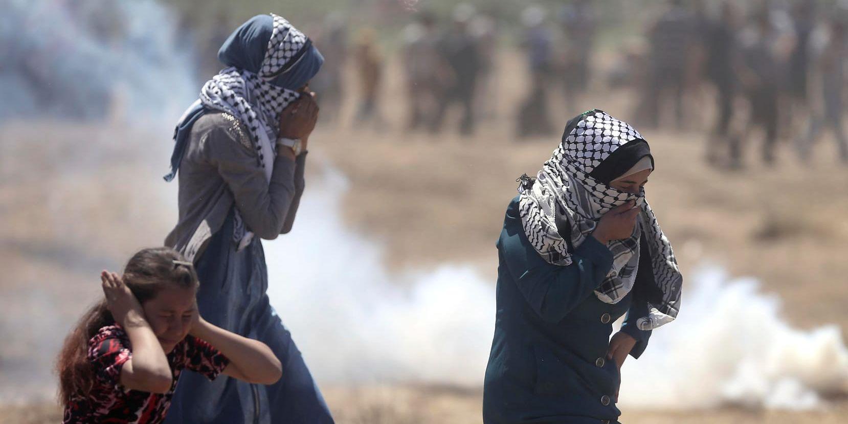 Palestinska kvinnor försöker skydda sig mot tårgas som avfyrats av israeliska soldater vid Gazas gräns mot Israel.