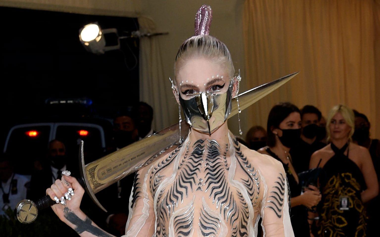 Pop-ikonen Grimes tänkte på avstånd och smittorisken och utrustade sig med både mask och svärd.