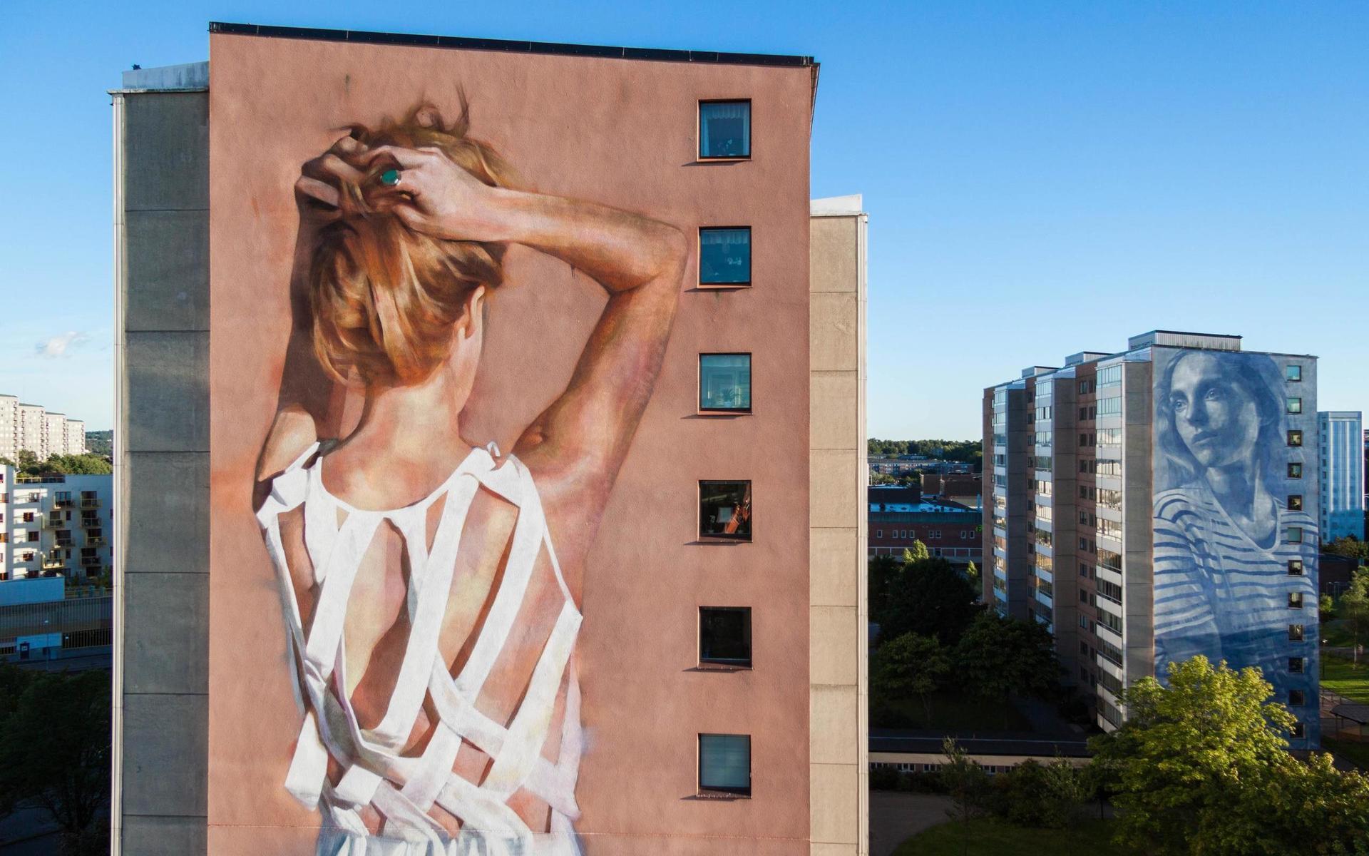 Vi ser konstnären Jarus från Kanadas jättemålning i Frölunda. I bakgrunden syns ett verk av Rone från Australien.