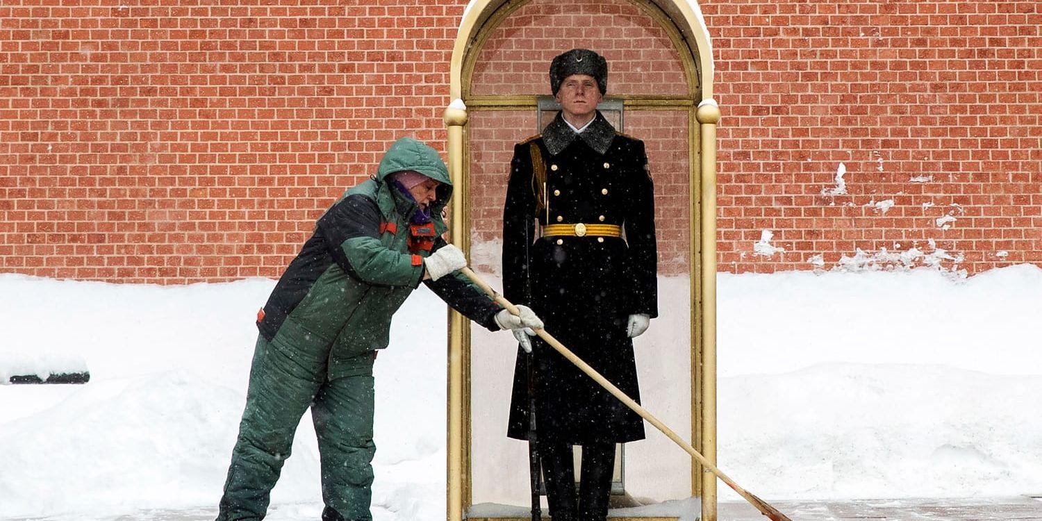 En man sopar bort snö framför en vakt vid Moskvamonumentet Den okände soldatens grav i februari 2021.