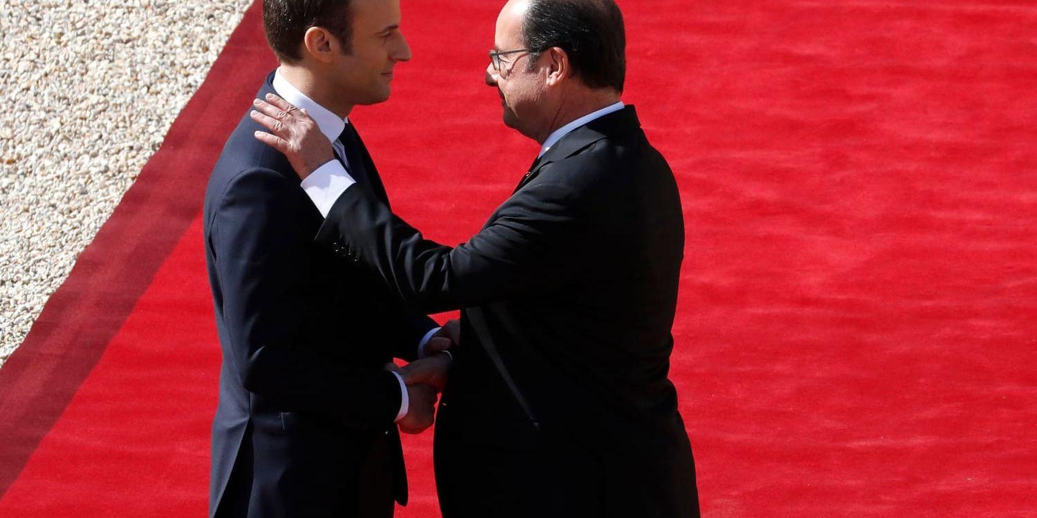Frankrikes president Emmanuel Macron skakar hand med sin föregångare François Hollande utanför Élyséepalatset i Paris. Arkivbild.