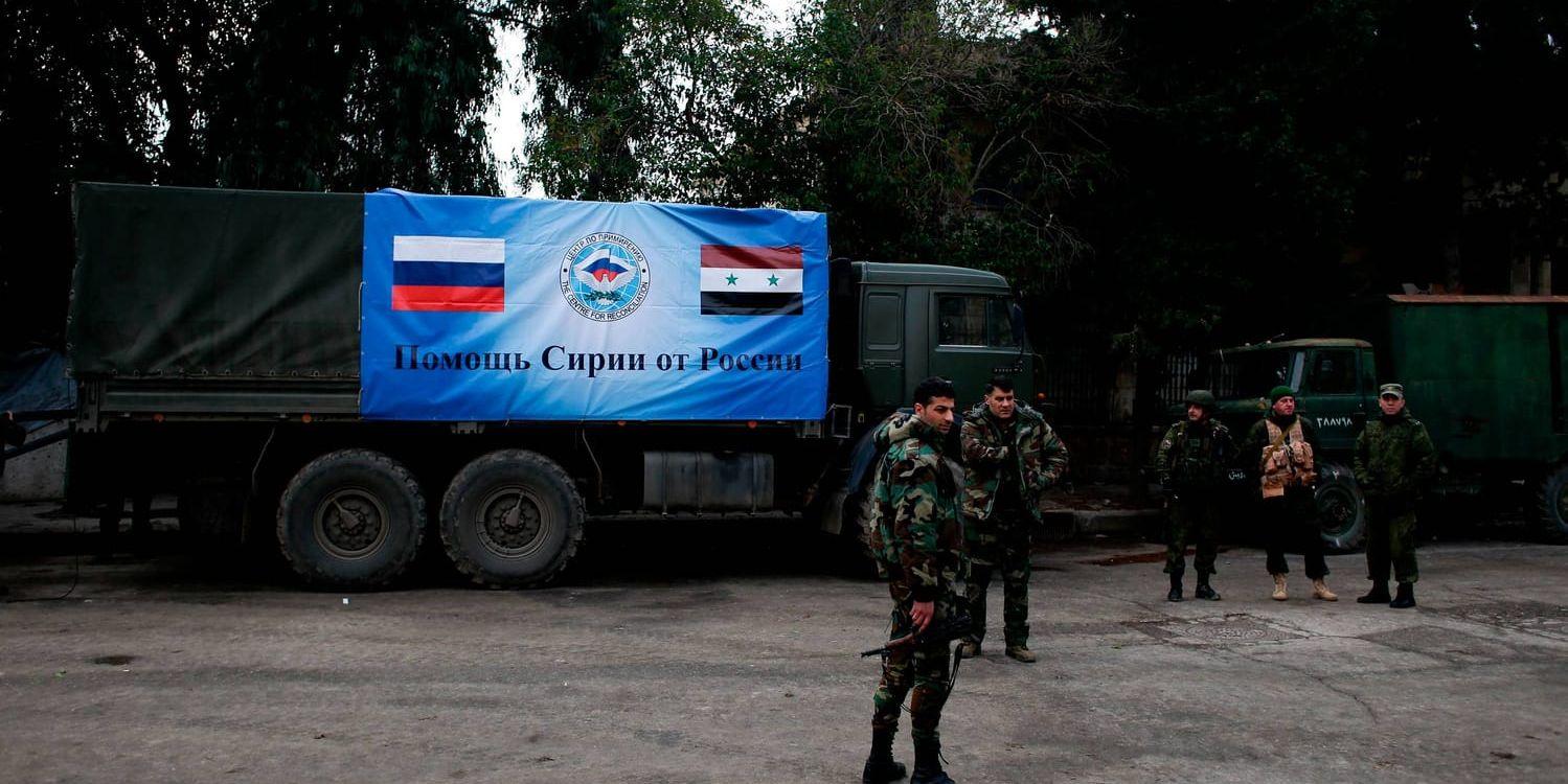 Ryska och syriska soldater intill lastbilar med förnödenheter i den syriska staden Aleppo i december.