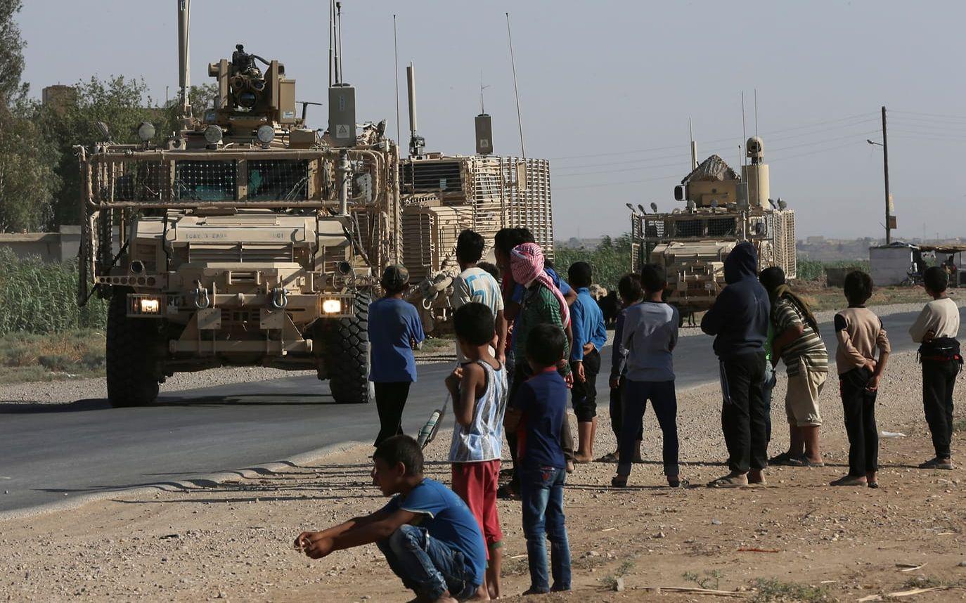 Syriska barn och ungdomar har samlats vid en väg för att titta på amerikanska bepansrade fordon som rullar mot al-Raqqa, där hårda strider rasar mot IS-terroristerna. FOTO: Hussein Malla/AP
