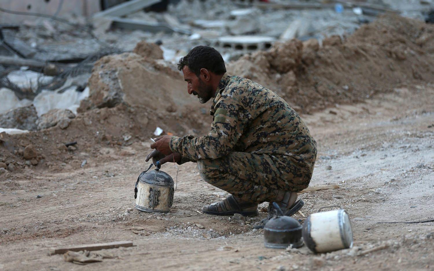 En soldat från de USA-stödda styrkorna desarmerar hemmagjorda sprängladdningar i al-Raqqa. FOTO: Hussein Malla/AP
