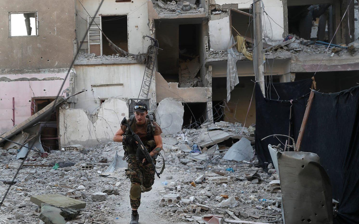 En soldat ur USA-stödda SDF (Syrian Democratic Forces) rycker fram under strider i al-Raqqa.
