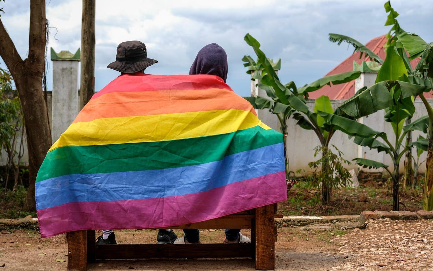 Ett homosexuellt ugandiskt par täcker sig med en prideflagga när de poserar för ett fotografi i Uganda lördagen den 25 mars 2023.