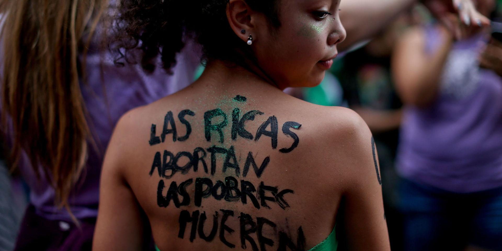 I bilden från pro-abortprotesterna i Buenos Aires den 10 april visas en ung kvinna med text på spanska målad på ryggen som betyder &quot;Rika kvinnor gör abort, de fattiga dör&quot;. 