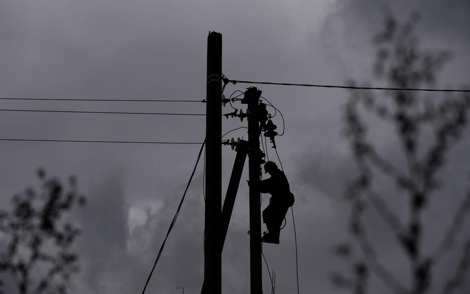 En man reparerar en strömkabel som skadats i en tidigare rysk attack, i Sjostka i norra Ukraina i oktober 2025.