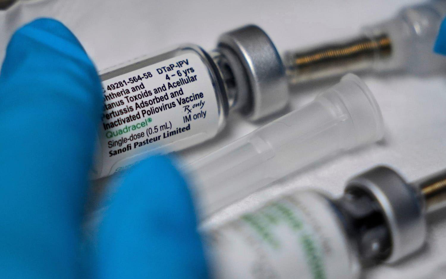 En liten behållare med poliovaccin som vidrörs av en blå handske.