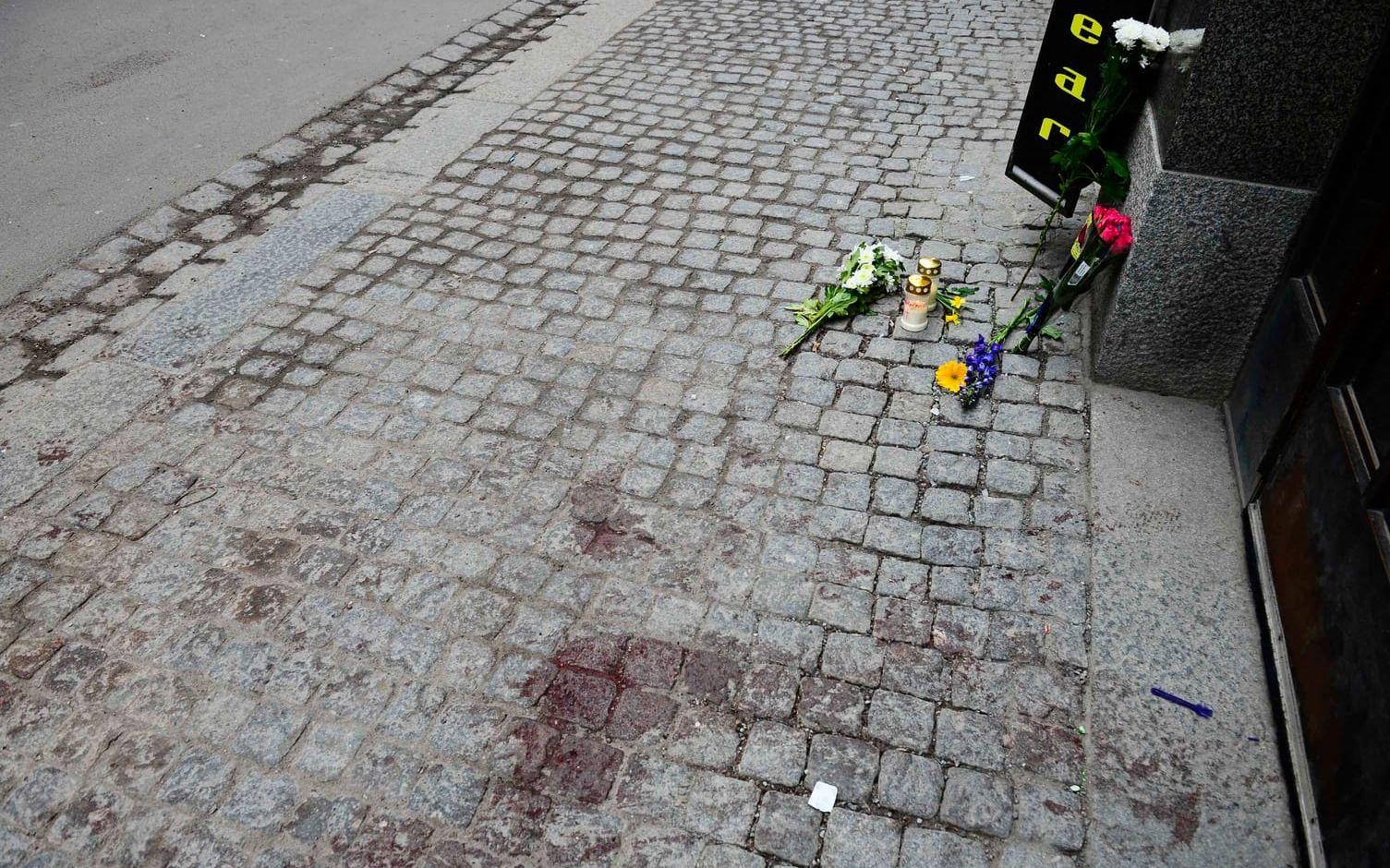 Blodspåren syns fortfarande på Drottninggatan. Intill har människor lämnat blommor för att hedra offren. Bild: Stefan Berg