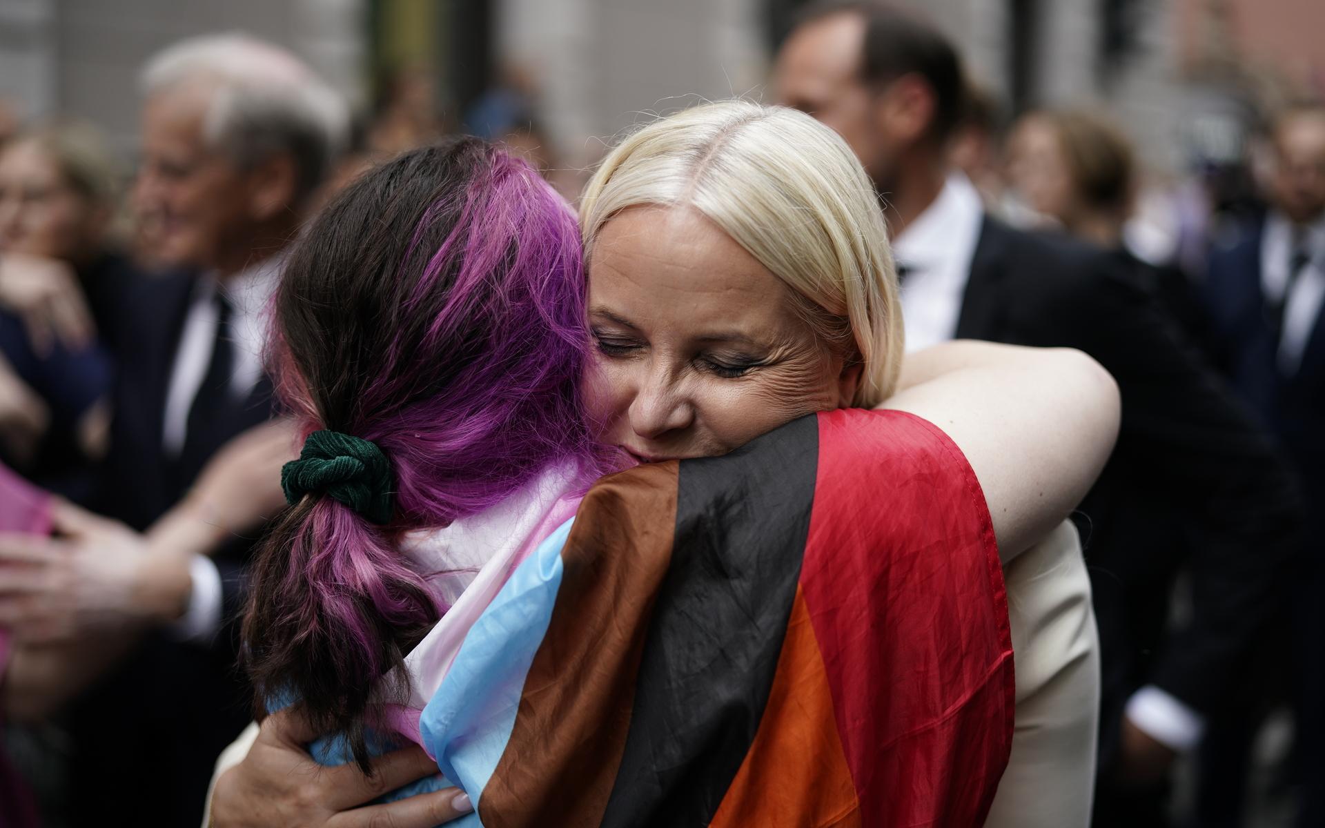 Kronprinsessan Mette-Marit kramar om en person på platsen där människor har samlats efter terrordådet.