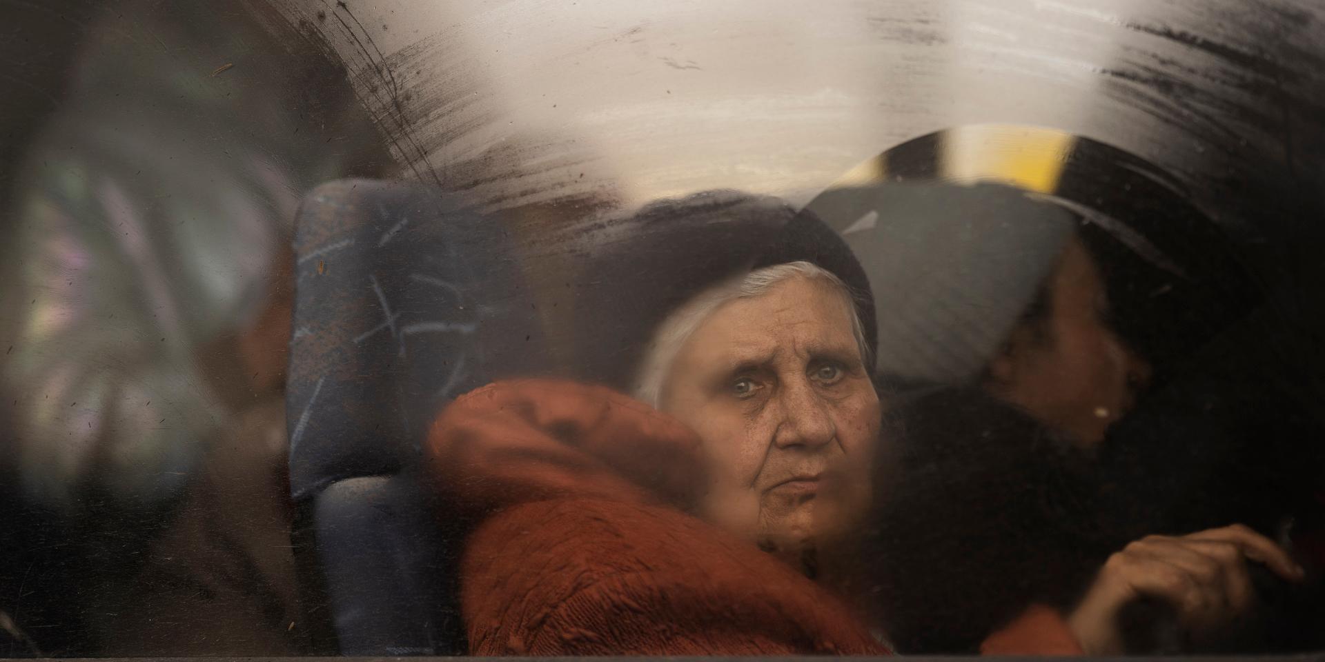 En äldre kvinna på flykt från Mariupol tittar sorgset ut genom fönstret på bussen som har tagit henne till staden Zaporizhzhia, drygt 20 mil från hemstaden som kontrolleras av ryska förband och separatister och med stöd av bland andra legosoldater.