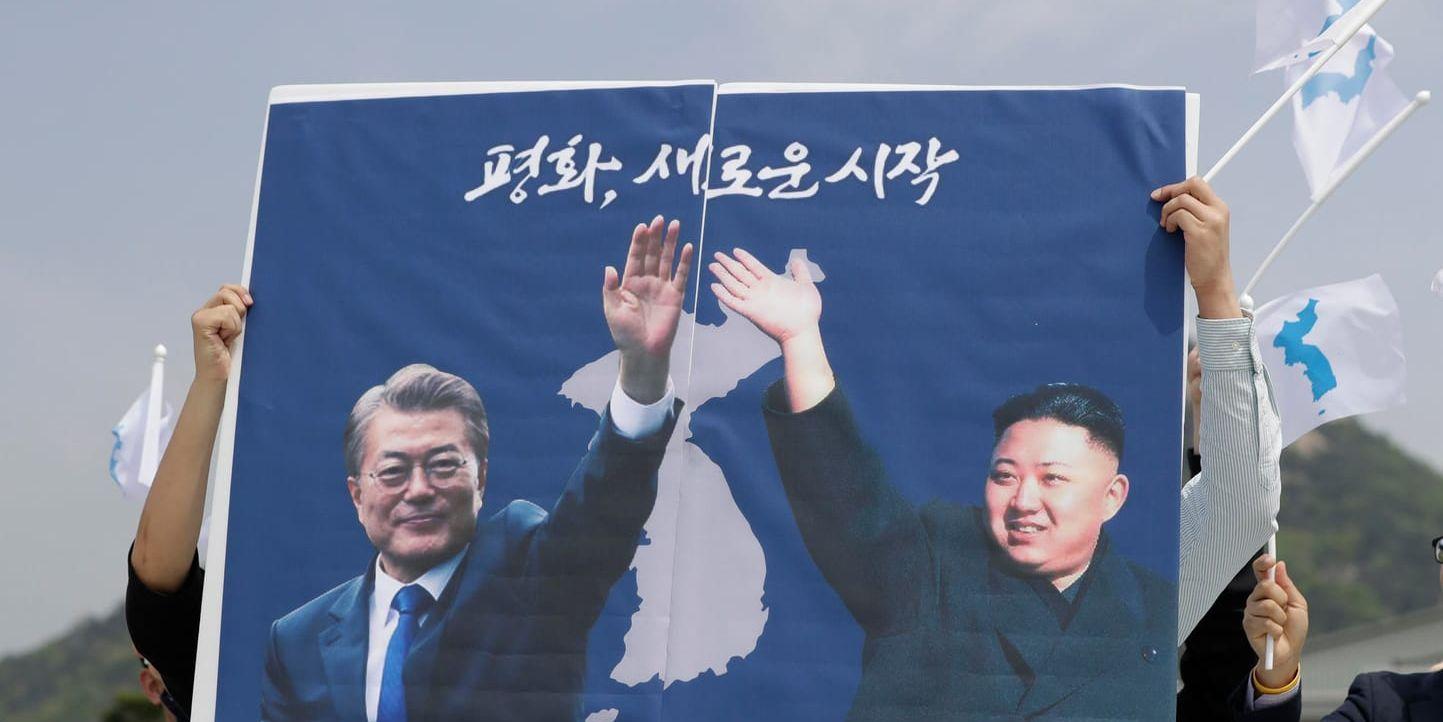 Sydkoreaner håller upp ett montage som föreställer de båda ledarna på Koreahalvön. "En ny start" står det på skylten.