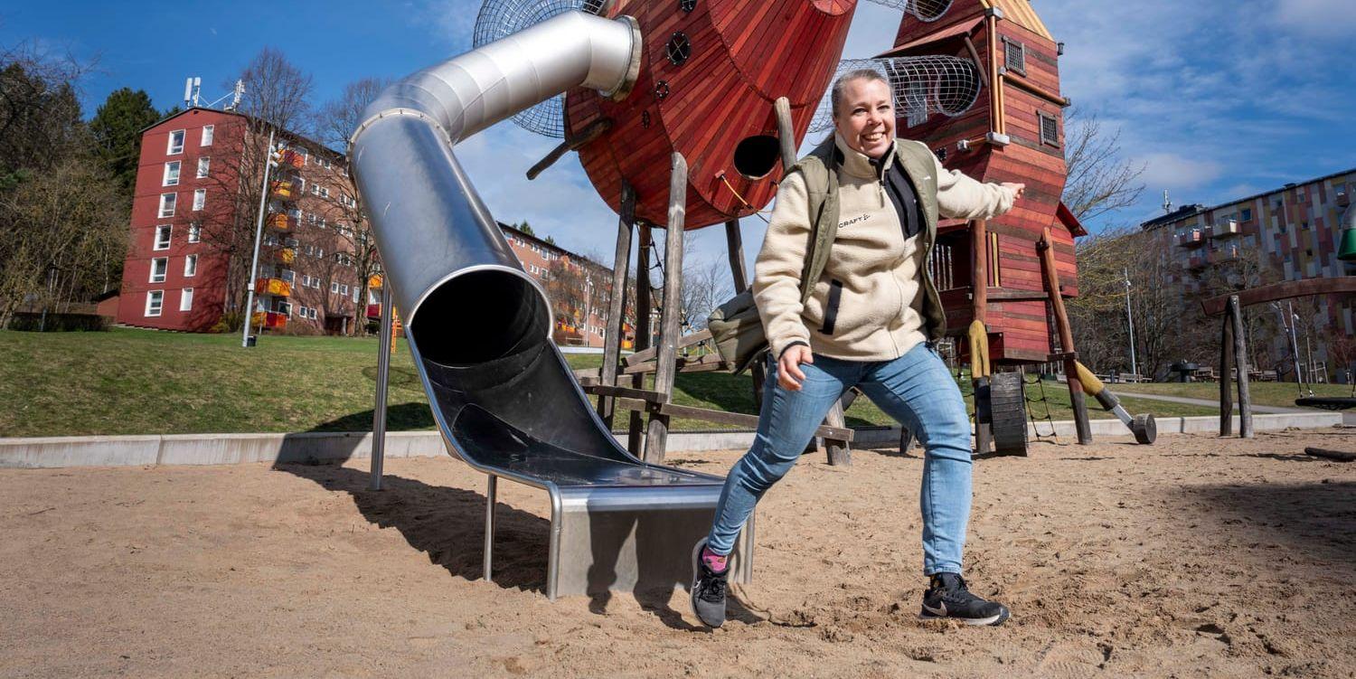 En lekplats och en kvinna i beige tröja och blå jeans.