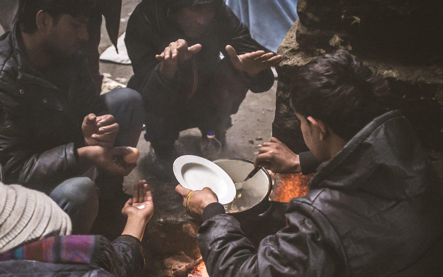 Människor lagar mat vid lägerelden i ett övergivet lager i centrala Belgrad. Bild: Igor Čoko 