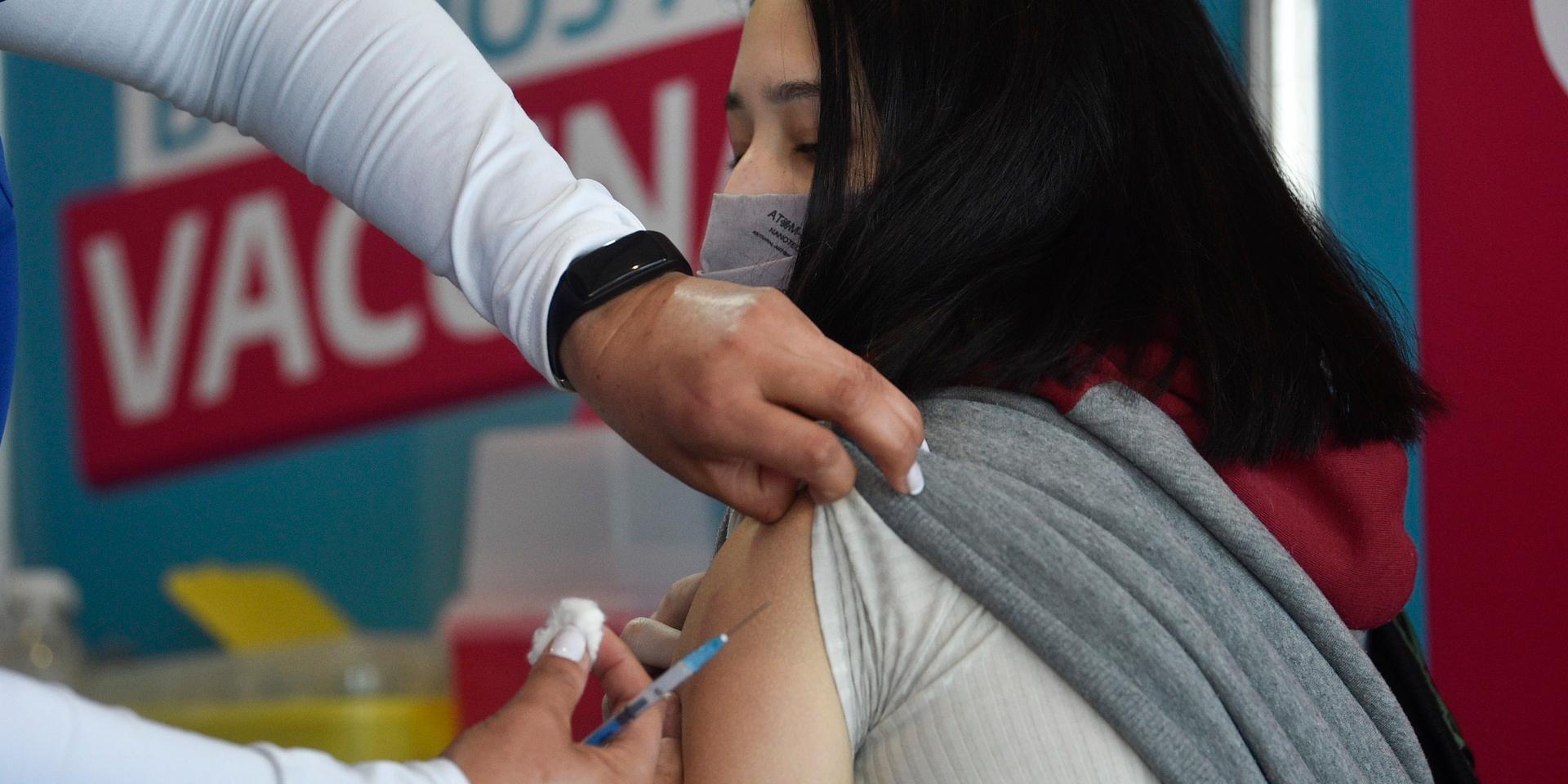 En ung kvinna i Argentina får en dos vaccin som donerats av USA.