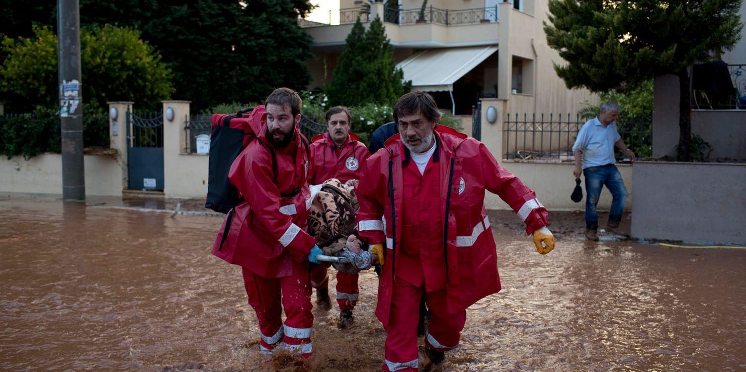 Röda Korset-personal bär en äldre man till en väntande ambulans i Mandra väster om Aten tidigare i veckan.