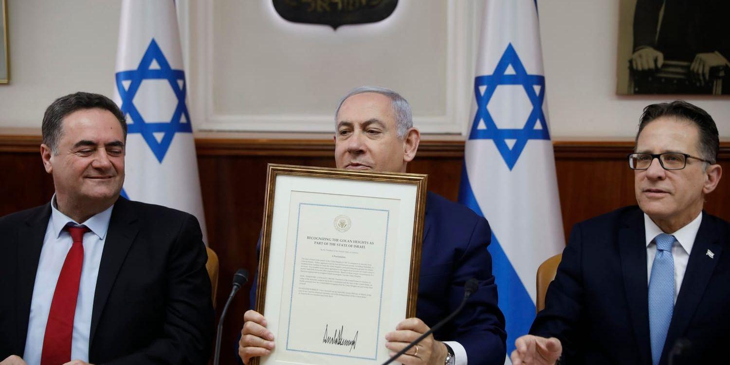 Israels premiärminister Benjamin Netanyahu håller upp den amerikanska kungörelsen, signerad av Donald Trump. Arkivbild från 14 april.