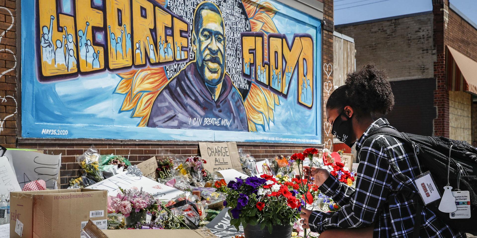 En ung kvinna lägger ner blommor framför en muralmålning av George Floyd i Minneapolis där han dog i samband med ett polisingripande. Många världsledare fördömer händelserna kring Floyds död. 