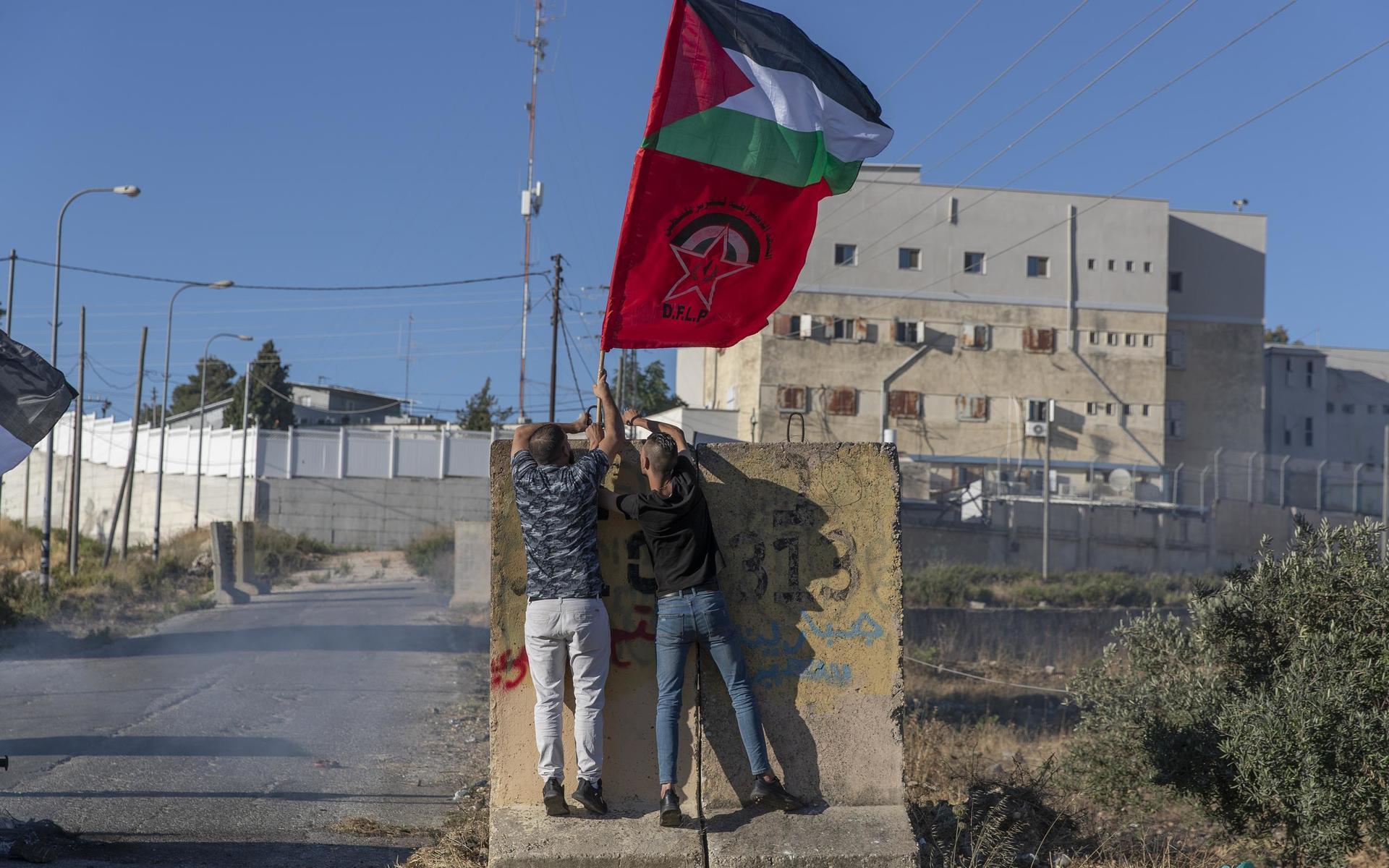 Palestinier hissar flagga vid ingången bosättningen Beit El.