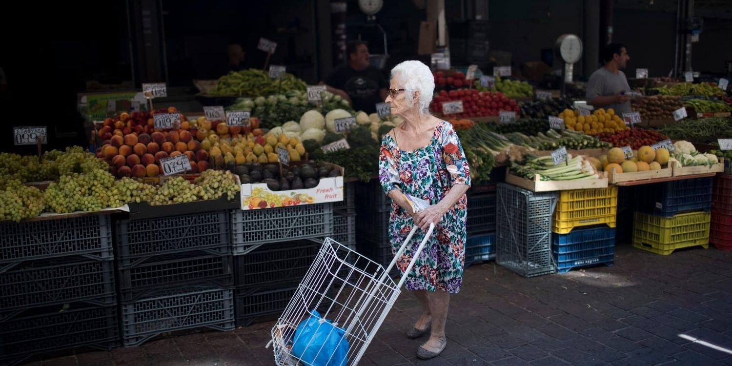 En äldre kvinna handlar frukt och grönsaker i Aten. Många grekiska pensionärer är missnöjda med de åtstramningar som har genomförts under åren av stödprogram. Arkivbild.