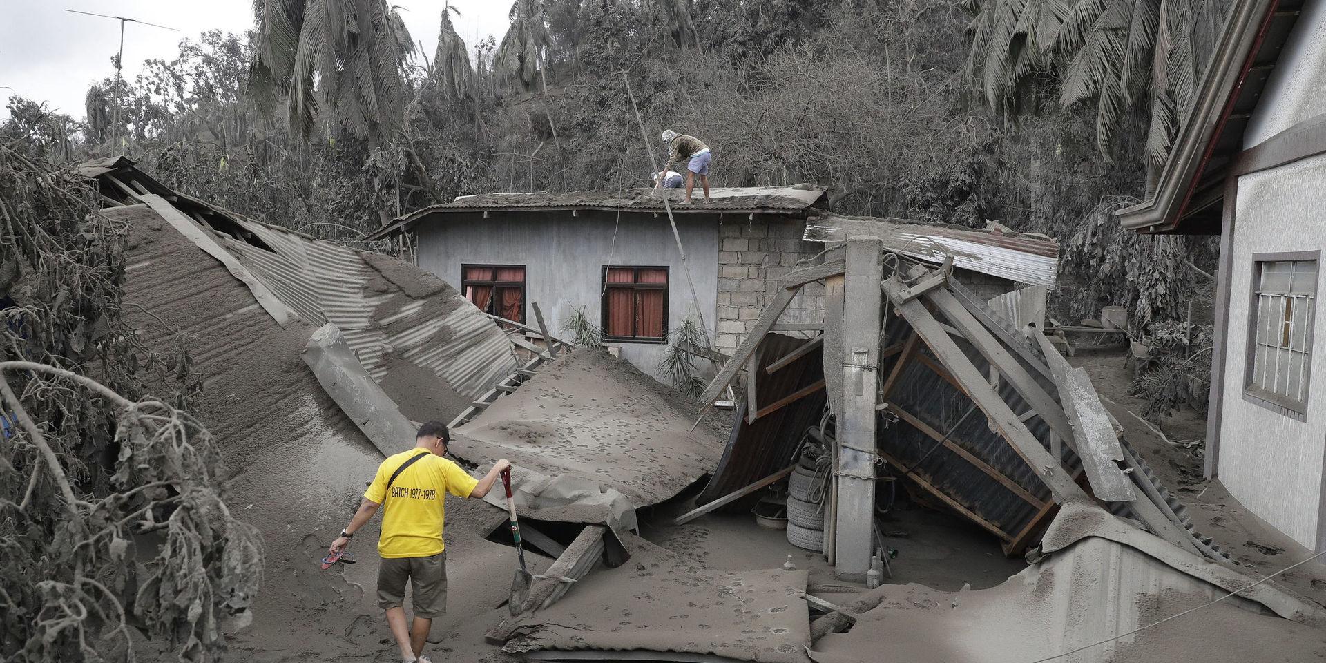 Invånare vid ett hus som förstörts av vulkanaska i södra Filippinerna. 