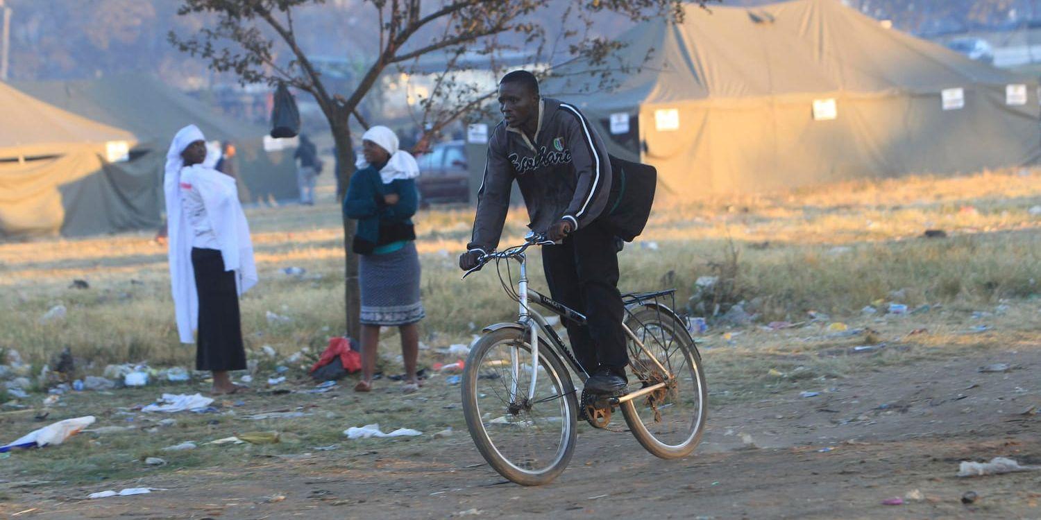 En man cyklar förbi en vallokal i Zimbabwes huvudstad Harare.