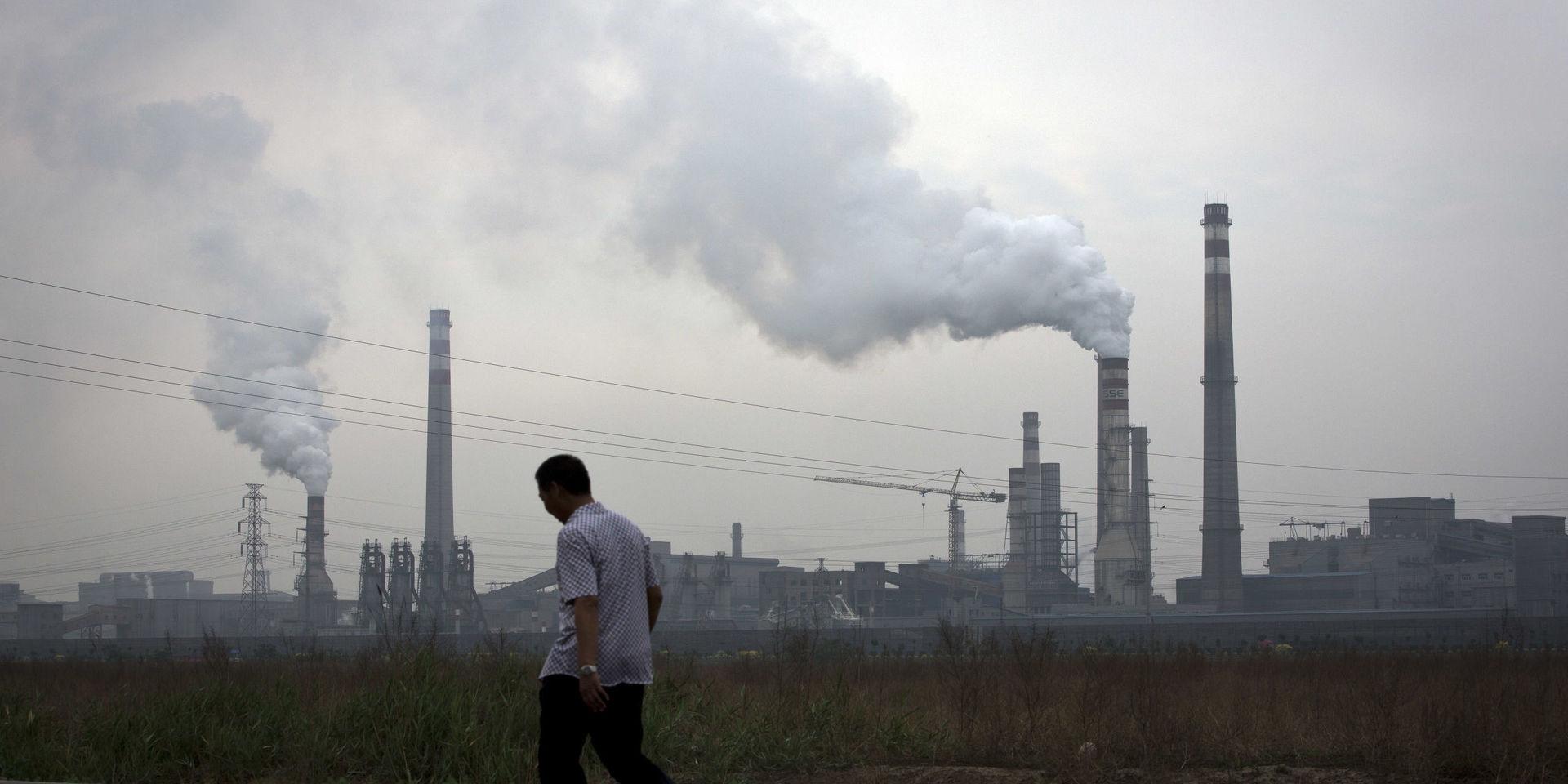 En man går förbi ett koldrivet stålverk i Tianjin, Kina.