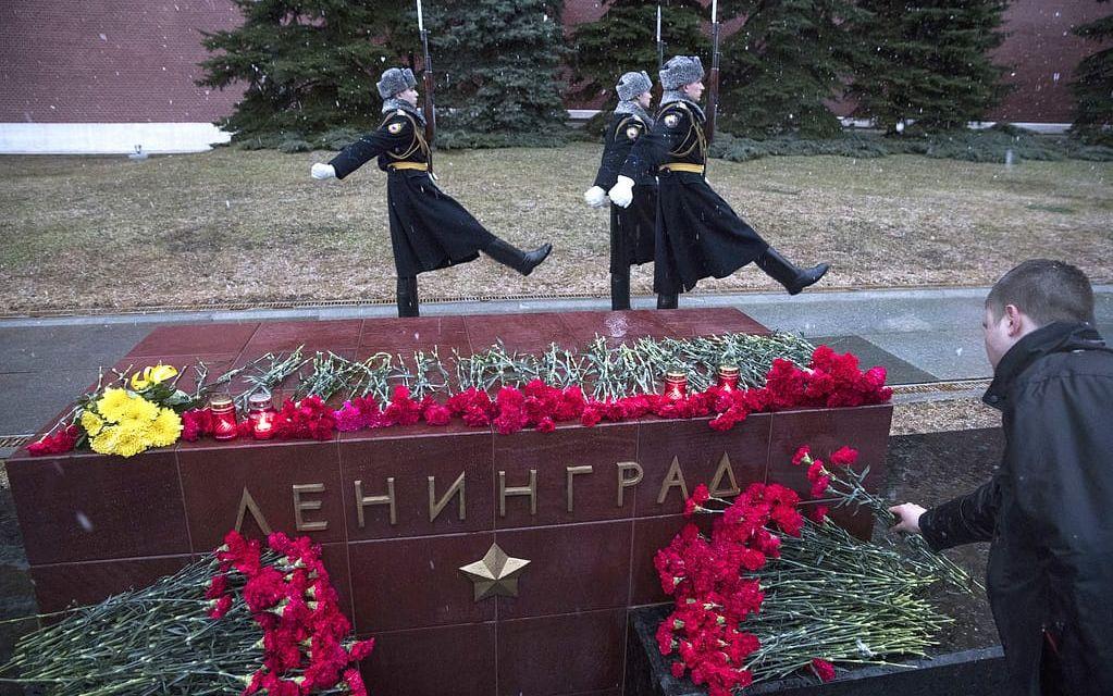 Skiftbyte för vakterna samtidigt som en man lägger blommor vid minnessten vid Kreml. Foto: TT
