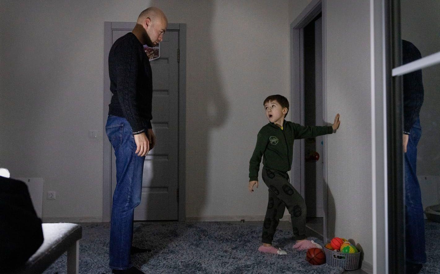 Pappa Nuri och sonen Timur spelar fotboll i hallens mörker med en liten batterilampa som enda ljuskälla.