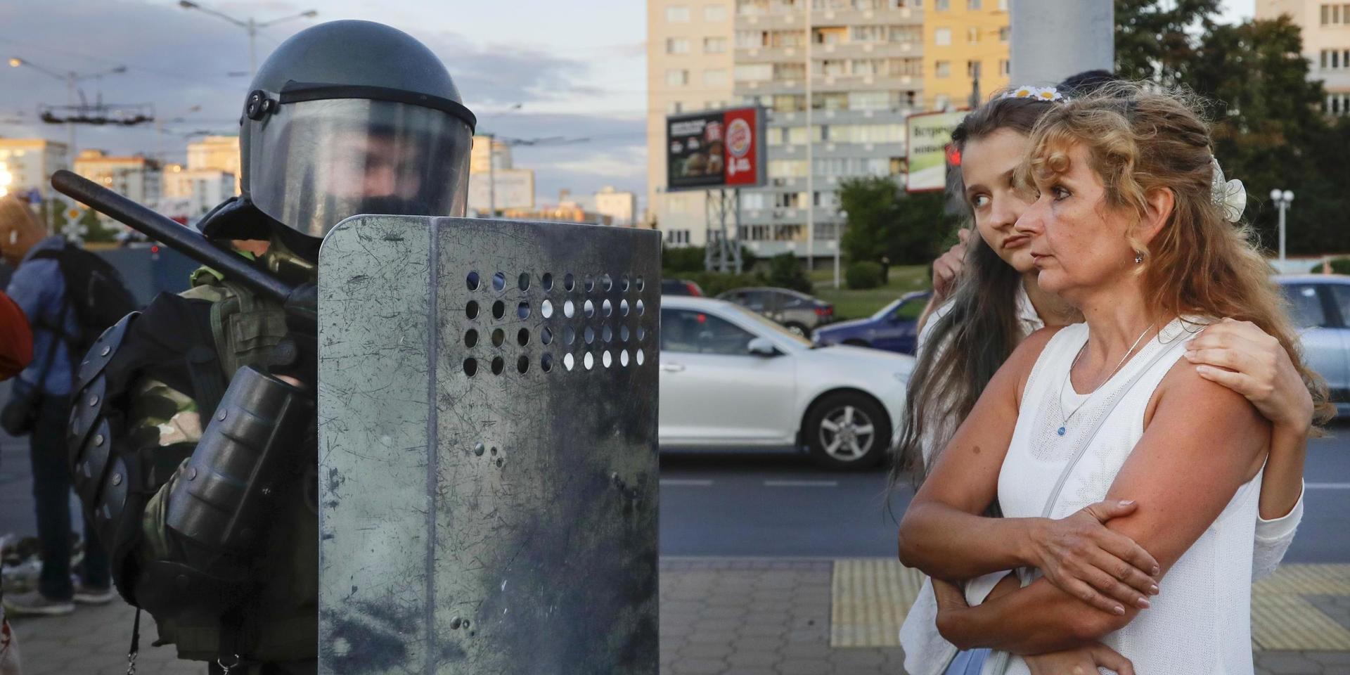 Två kvinnor pratar med en kravallpolis i centrala Minsk den 11 augusti.