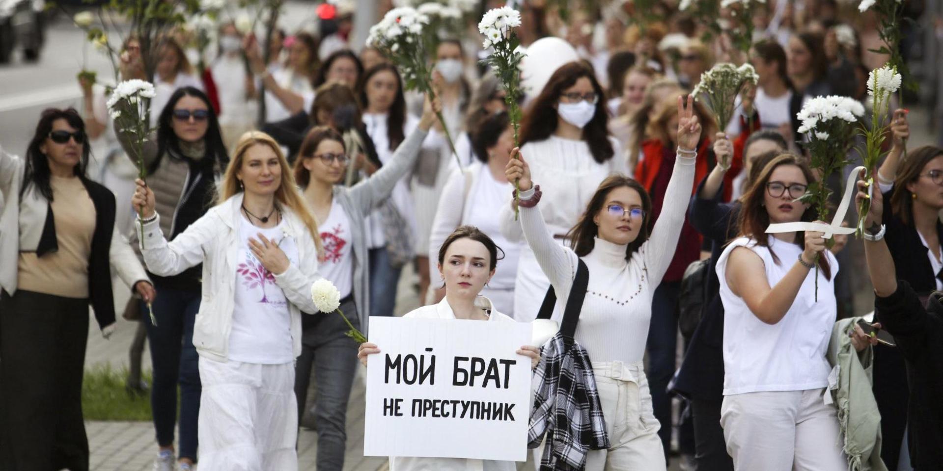 Belarusiska kvinnor, en av dem med en skylt med texten 'min bror är inte en brottsling', demonstrerar i Minsk den 13 augusti i solidaritet med de som gripits efter valet. 