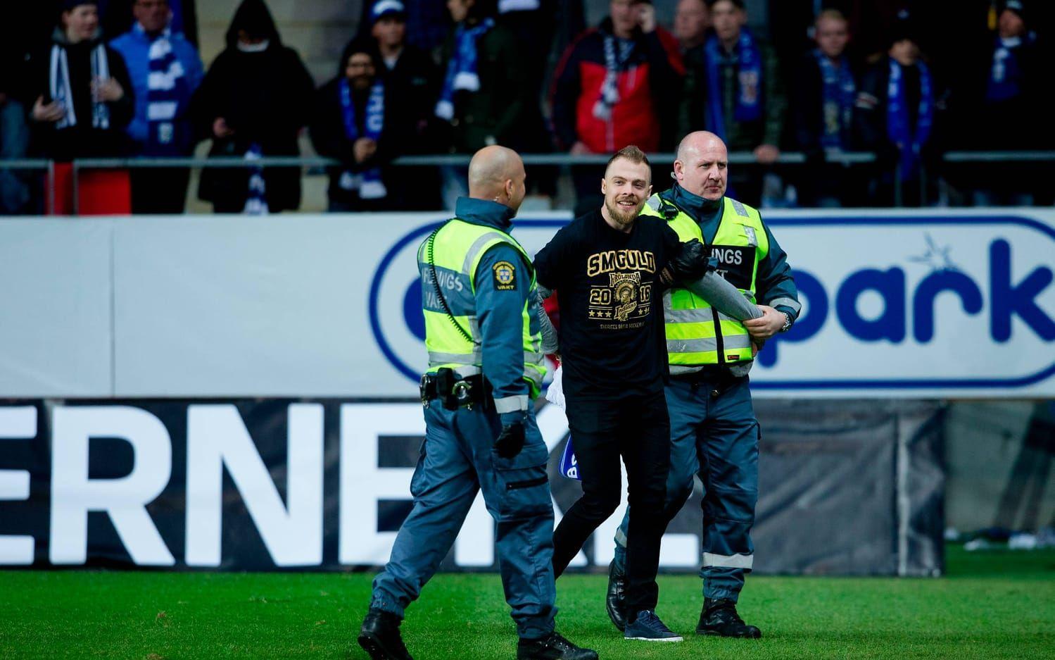 Frölundas guldhjälte Mats Rosseli Olsen förs bort av säkerhetspersonal sedan han stormat planen: Bild: Bildbyrån