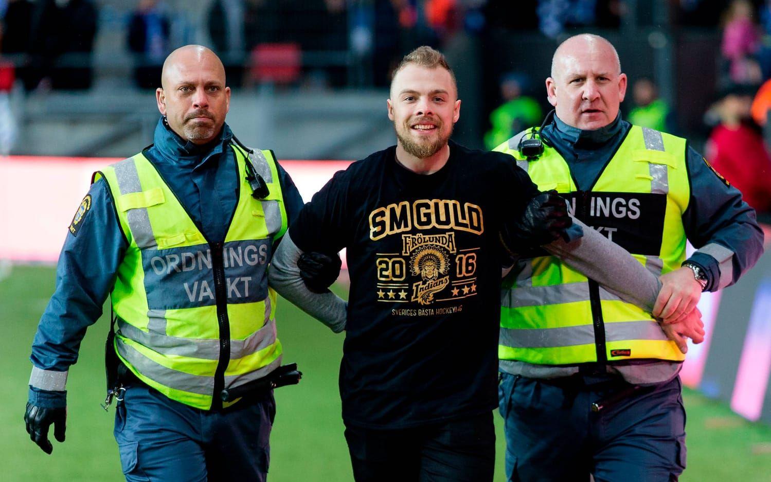 Frölundas guldhjälte Mats Rosseli Olsen förs bort av säkerhetspersonal sedan han stormat planen: Bild: Bildbyrån